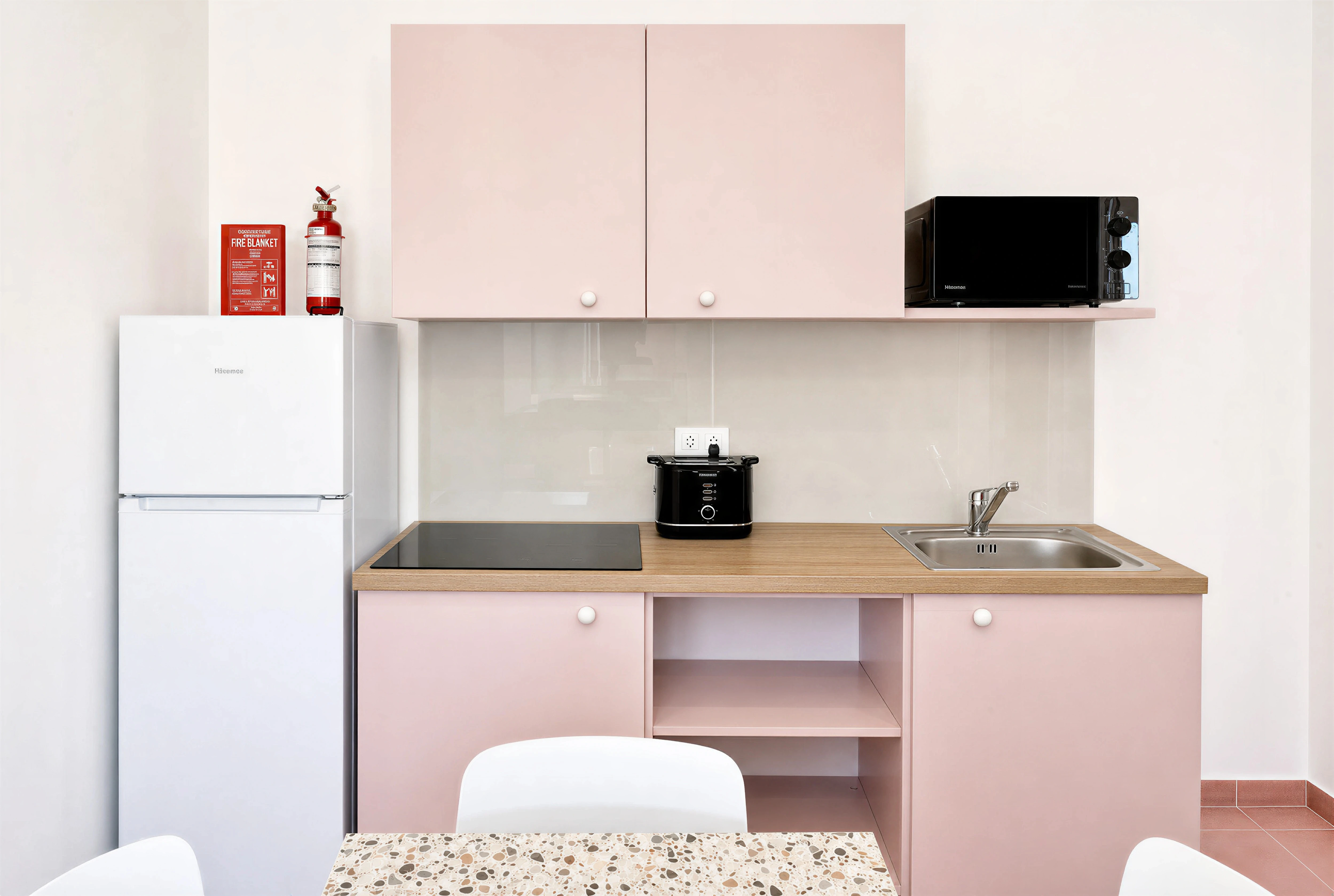 Pink kitchen with induction hob and terrazzo dining table at Flamingo Apartments