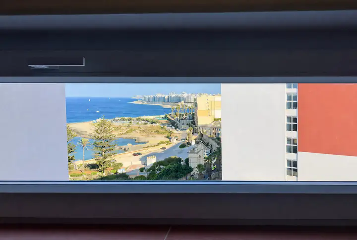 The bay, palm trees and coastline framed through a wide window